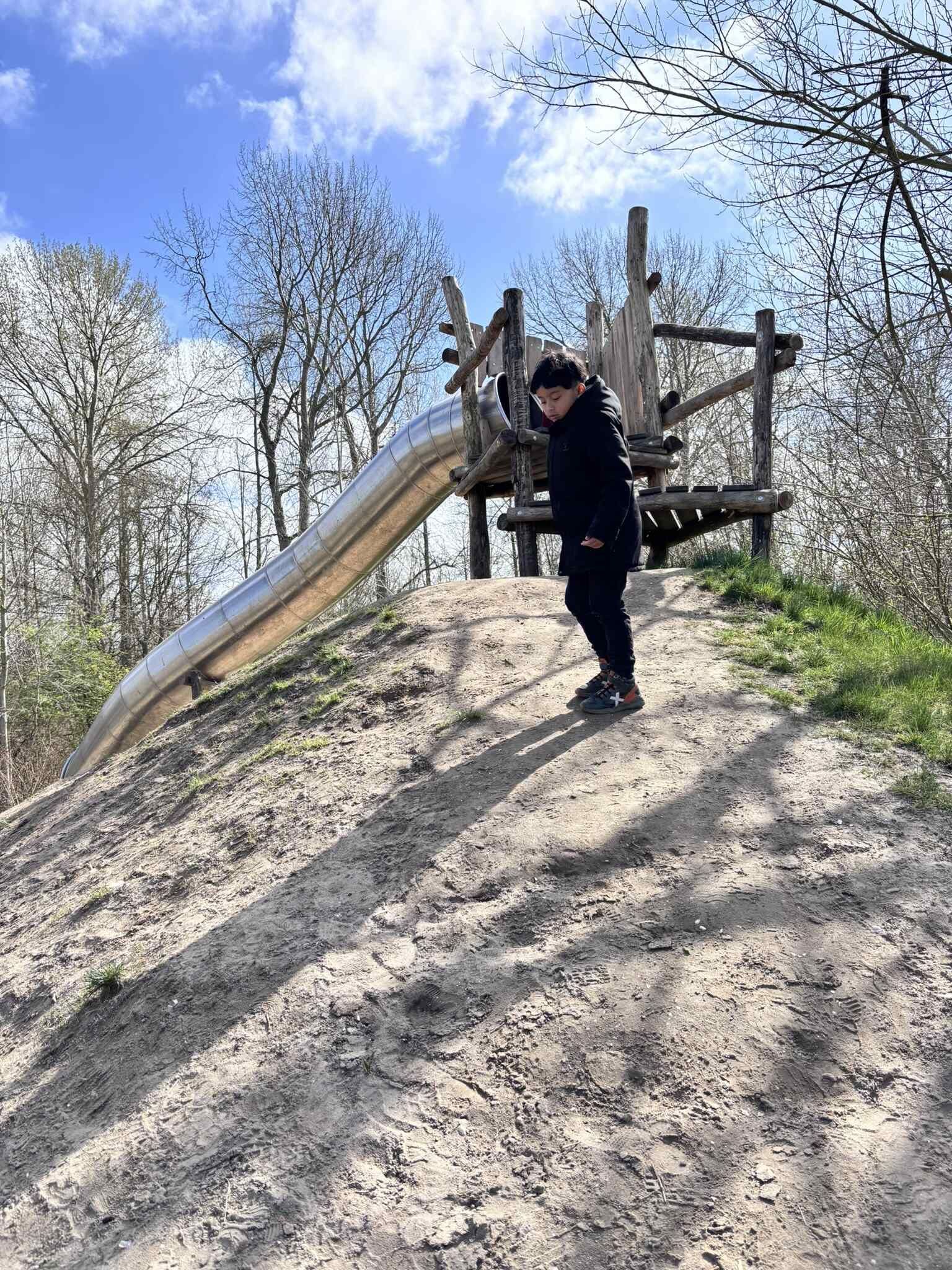 Een jonge jongen speelt op een glijbaan in een speeltuin.