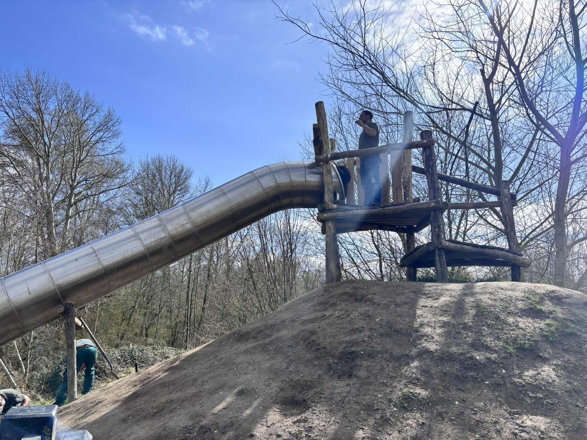 Een persoon staat bovenop een heuvel naast een glijbaan.