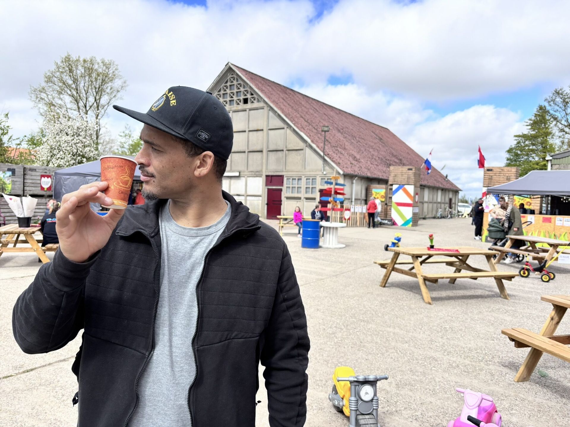 Een man met een baseballpet houdt een kopje koffie vast.