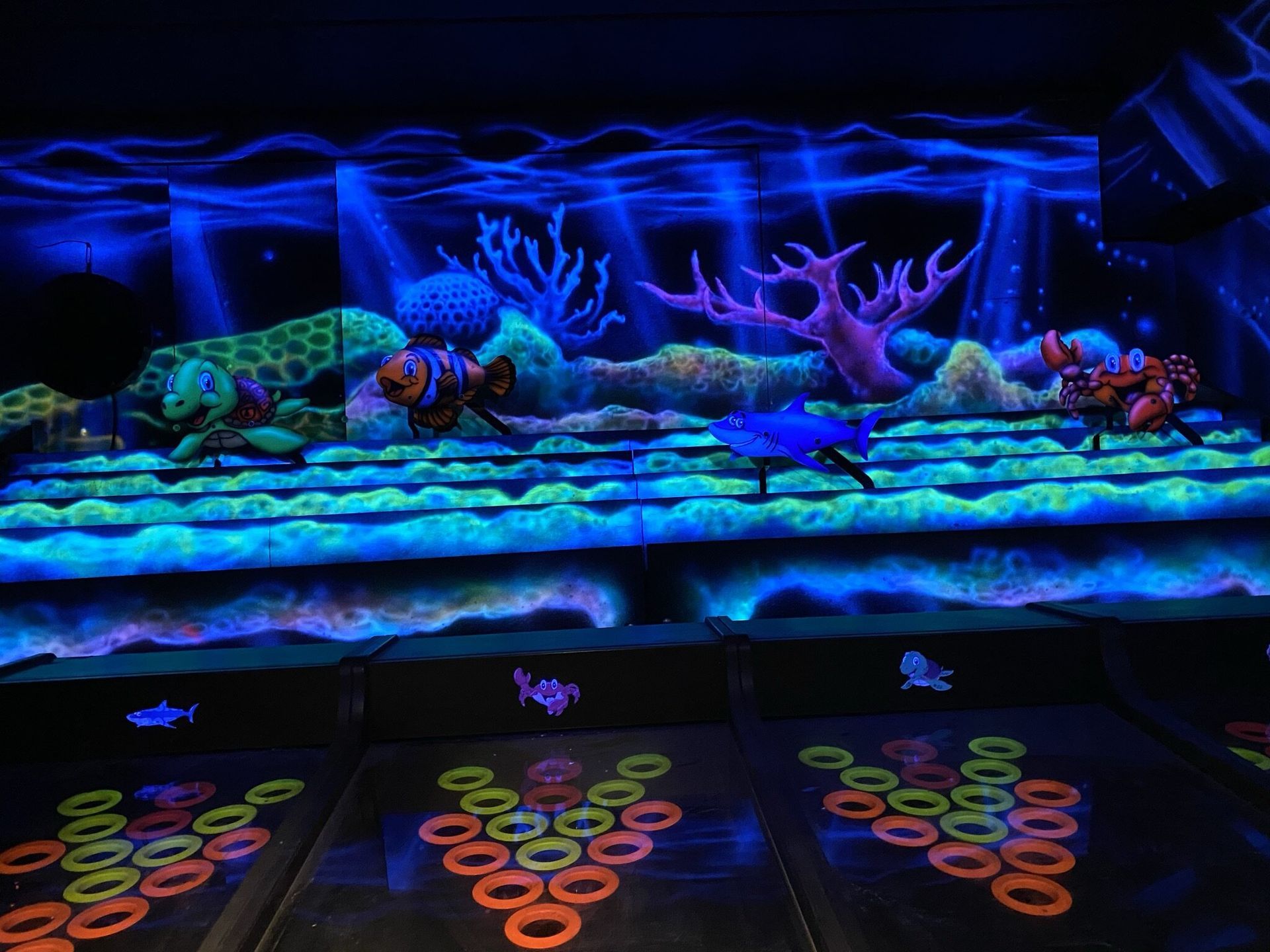 Een kamer met een schilderij van een koraalrif dat in het donker oplicht.