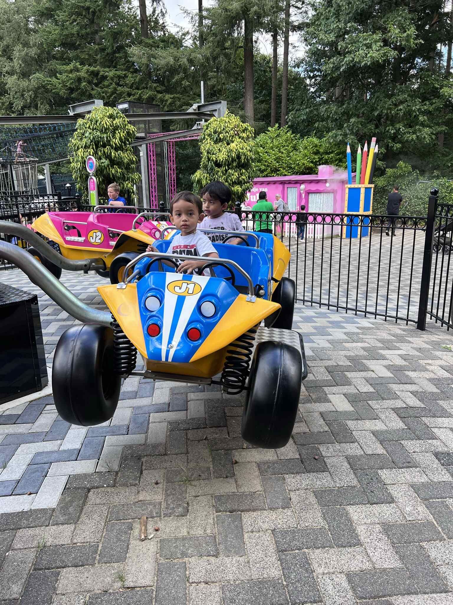 Een jongetje rijdt in een speelgoedauto in een pretpark.