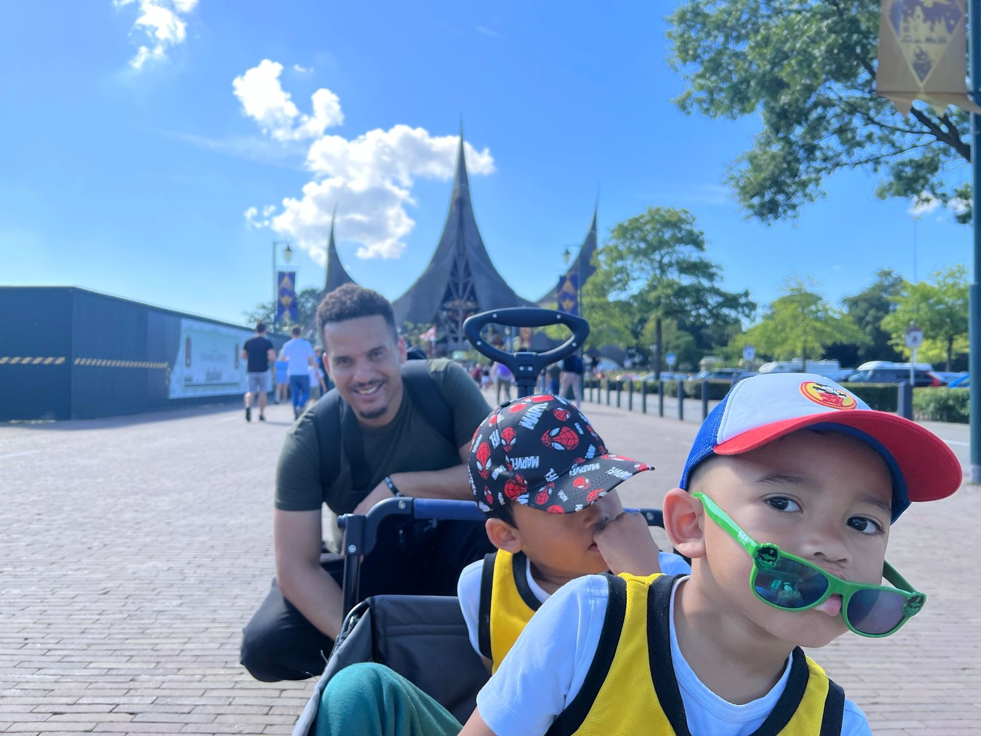 Een man duwt twee kinderen in een kinderwagen bij Efteling. 