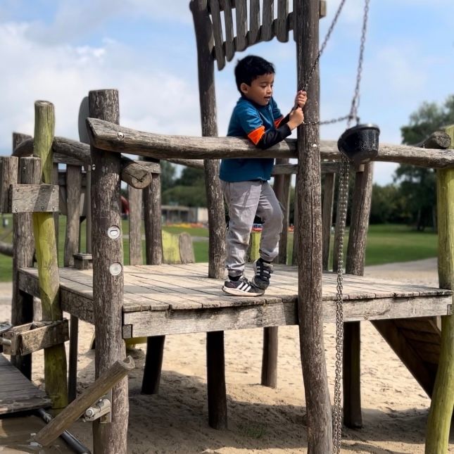 Een jonge jongen speelt op een houten speelplaats