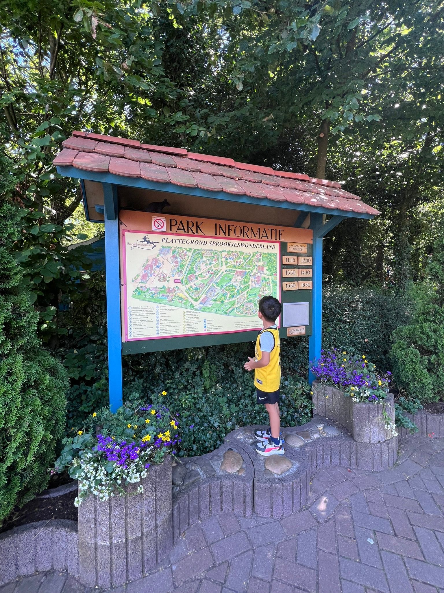 Een jonge jongen staat voor een grote kaart.