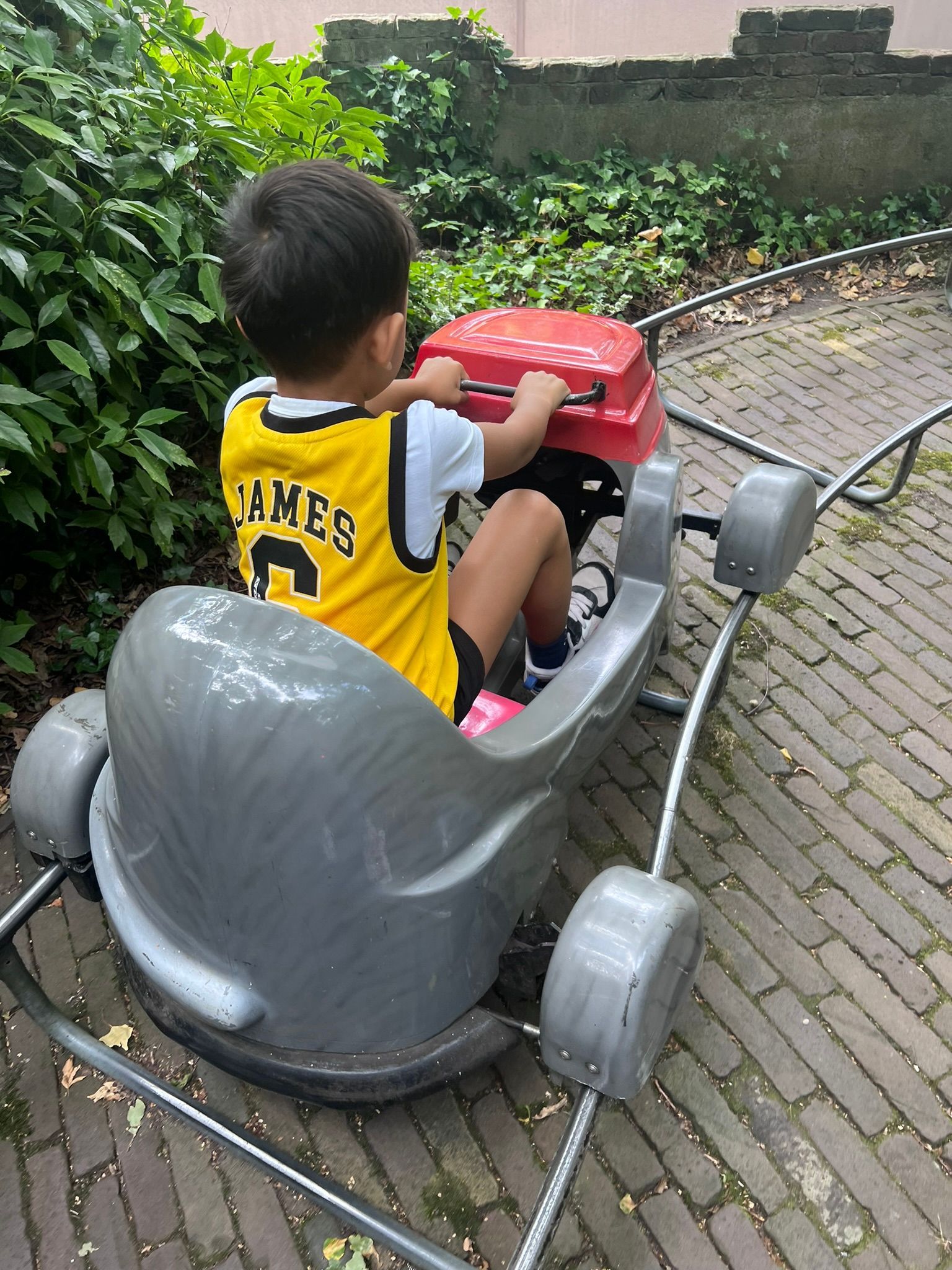 Een jonge jongen in een gele trui zit in een achtbaan.