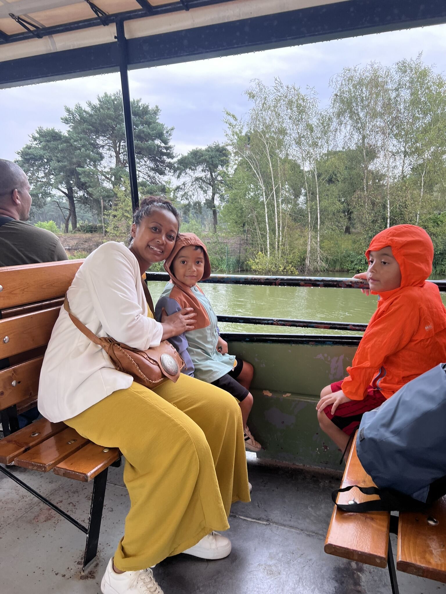 Een vrouw zit op een bankje met twee kinderen op een boot.