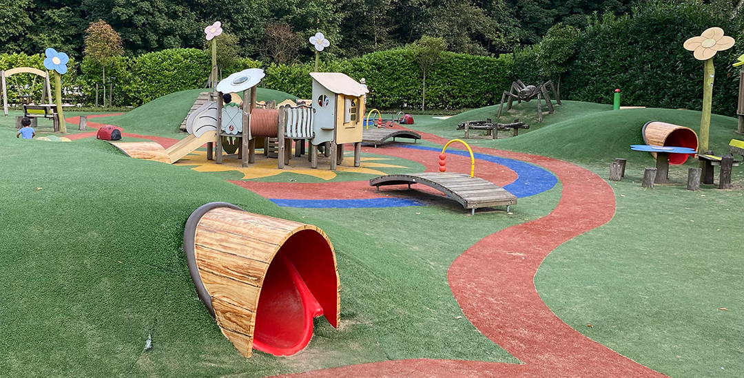 Een speeltuin met een treintje en een tunnel in het midden.