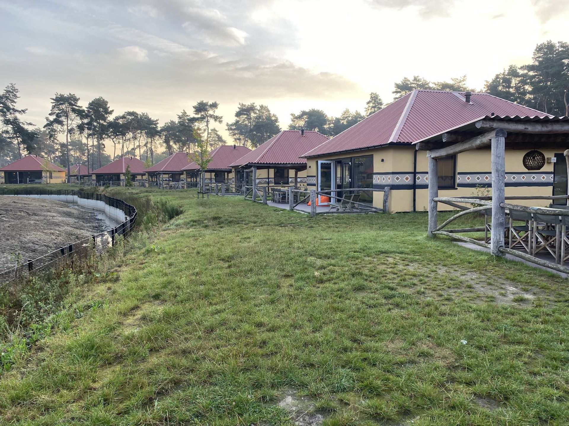 Een rij huizen met rode daken staan naast elkaar in een grasveld.