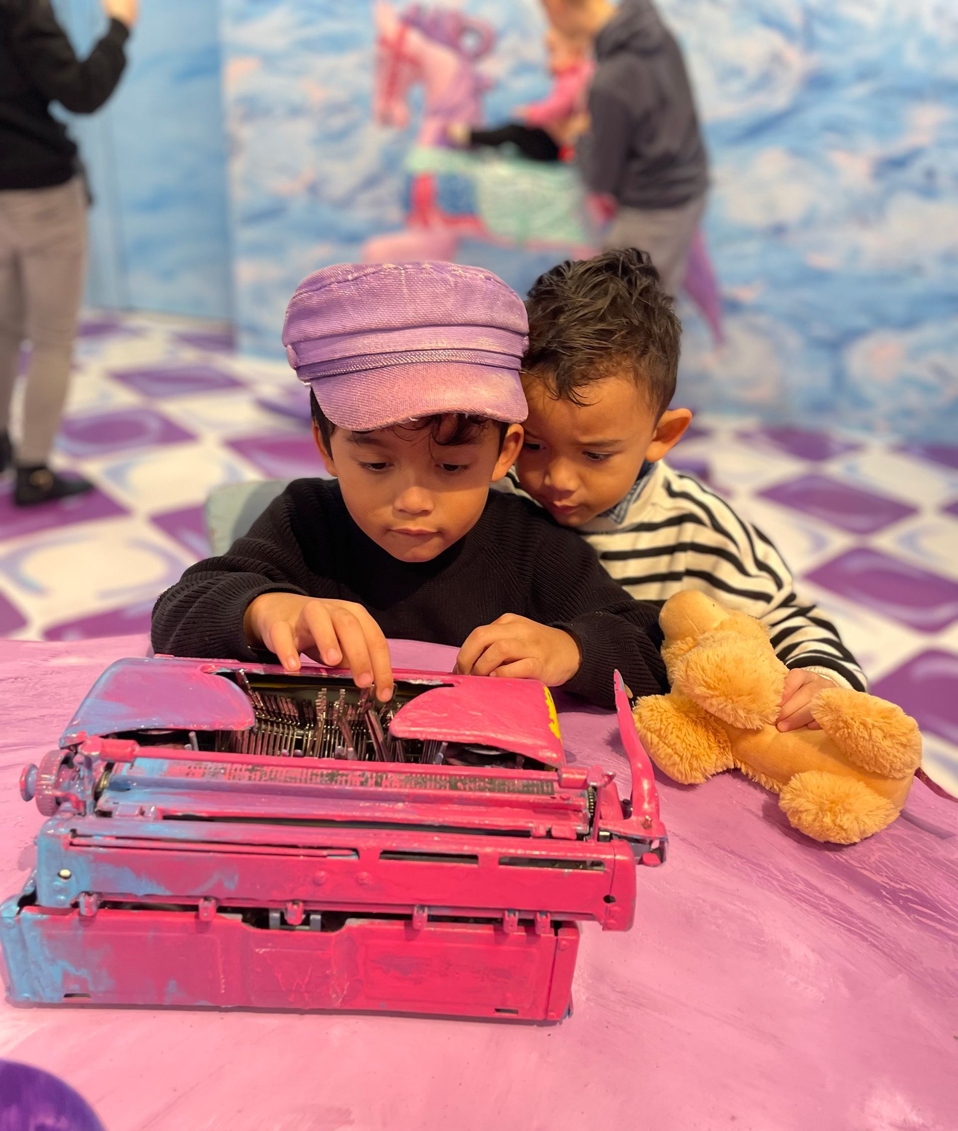 Twee jonge kinderen spelen met een roze typemachine.