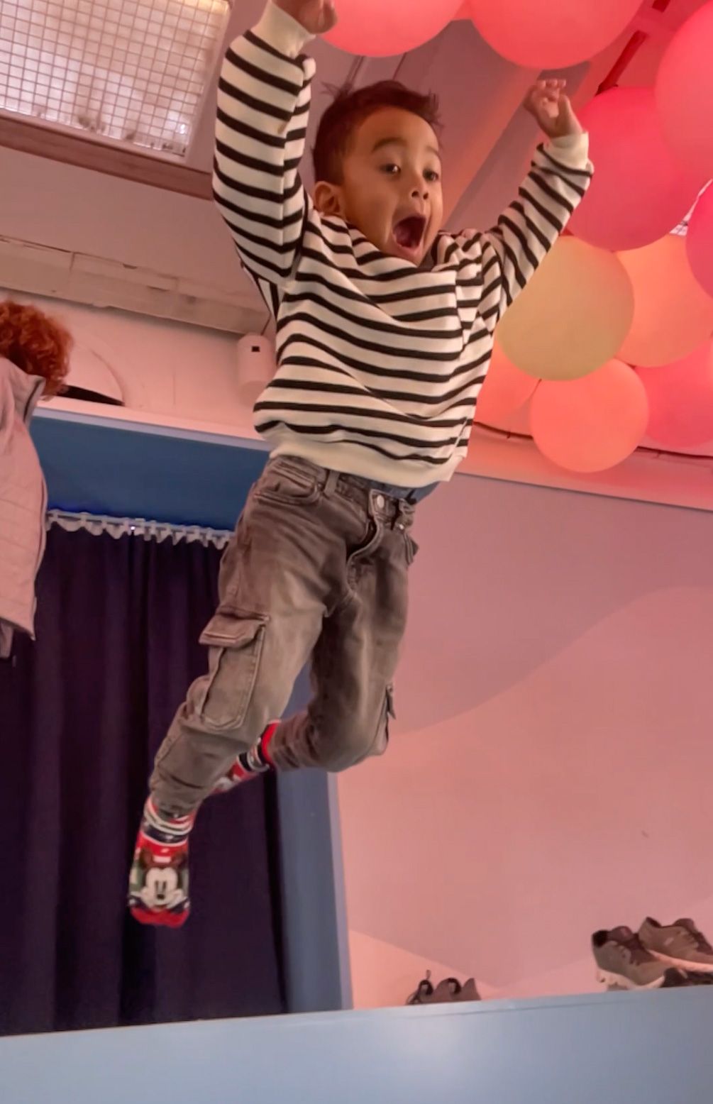 Een jonge jongen in een gestreept shirt springt in de lucht