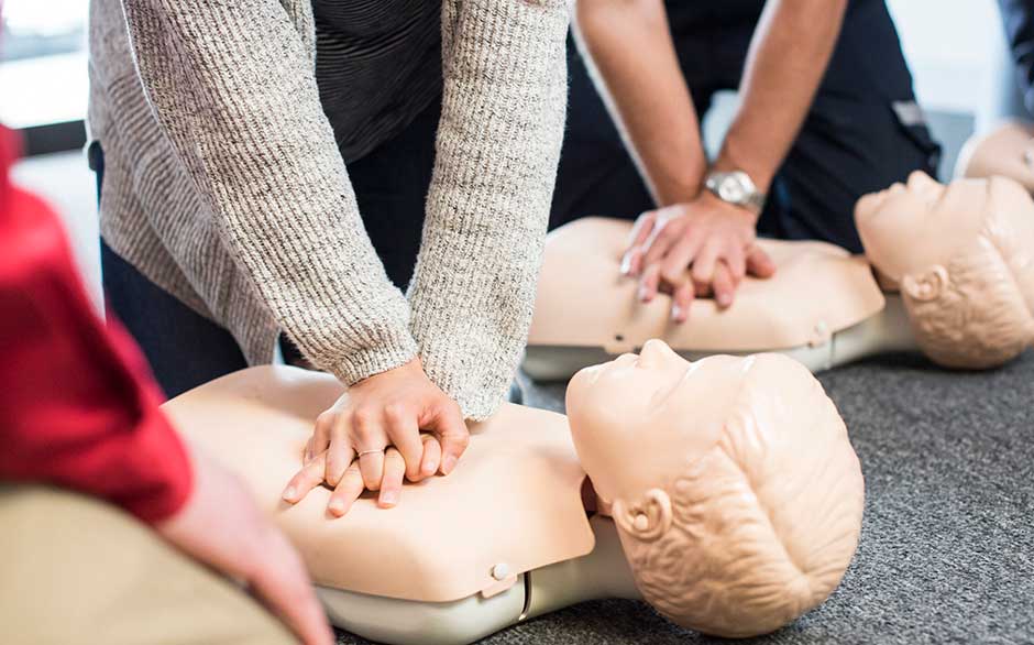 People practicing CPR on mannequins.