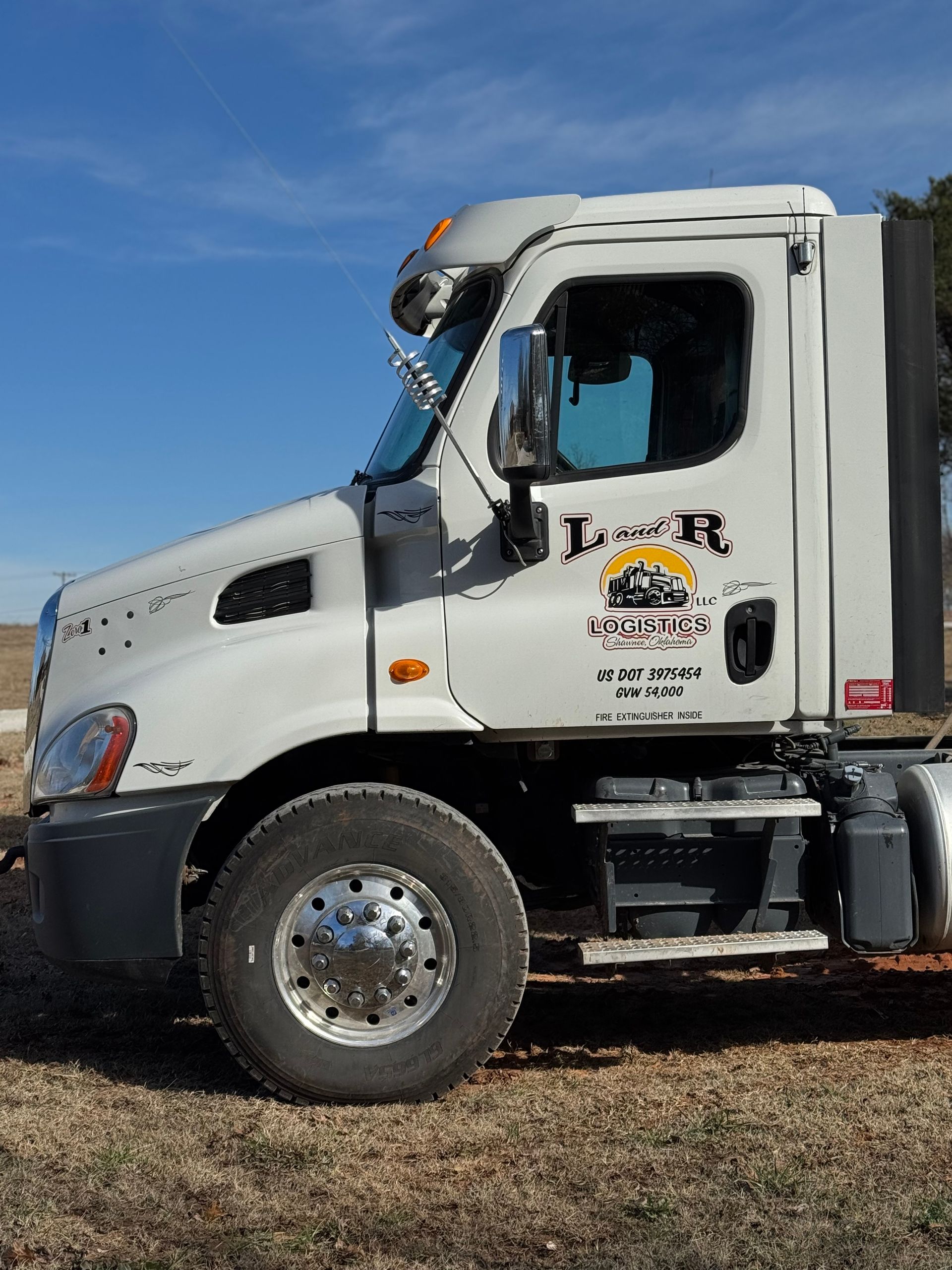 Red semi-truck driving on a road with a mountain backdrop.