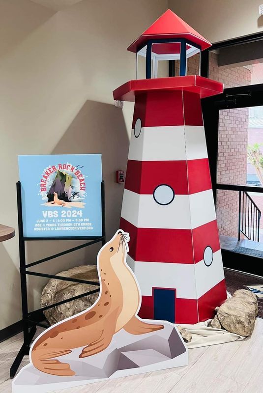 A cardboard cutout of a lighthouse and a sea lion with a sign for the