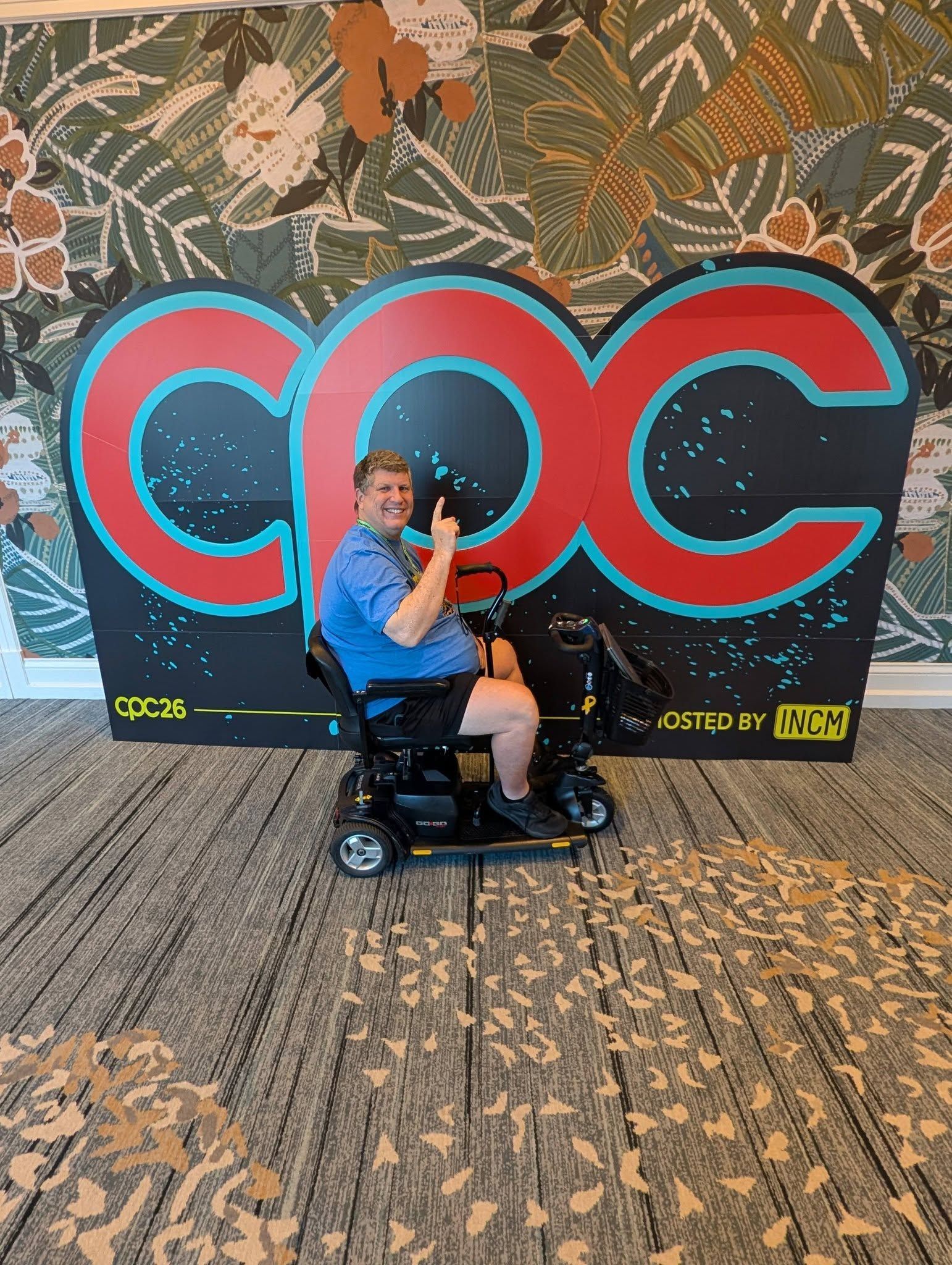 Man on mobility scooter gives thumbs up in front of a CPC logo backdrop.