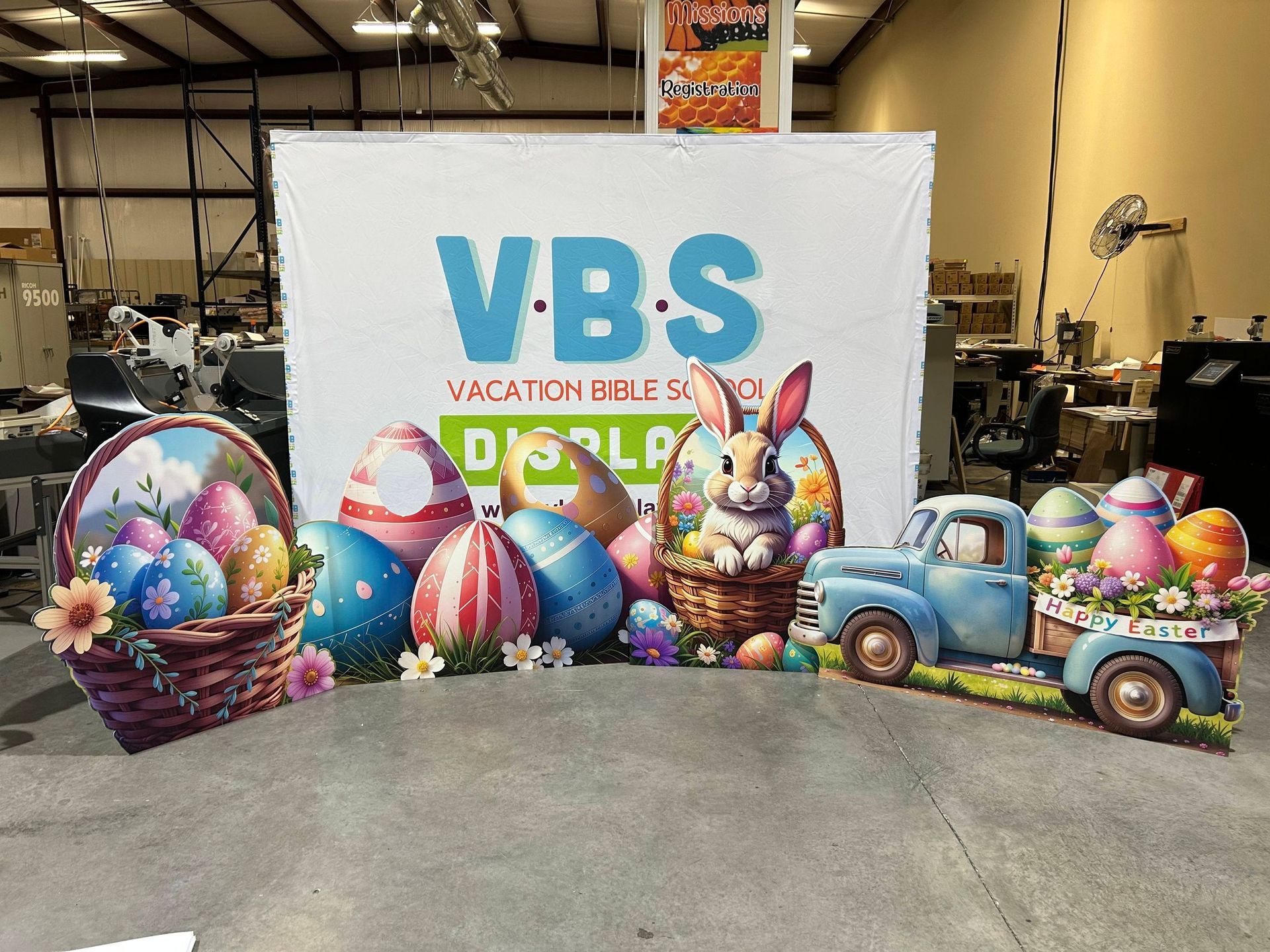 Easter-themed VBS display: a bunny, truck, basket, and eggs in front of 