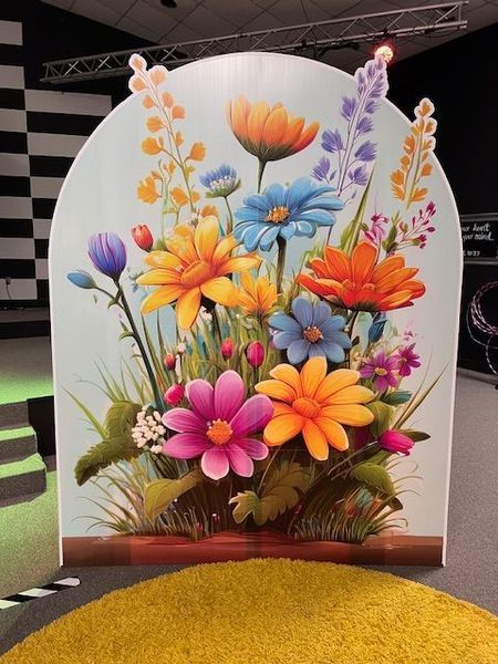 Floral painting on an arched panel, featuring colorful daisies and wildflowers.