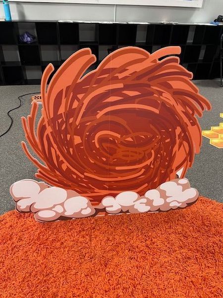 Orange cartoon tornado on an orange rug with white clouds at its base.