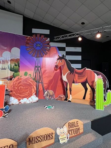 Stage set with cartoon horse, windmill, and desert backdrop for a children's event. 