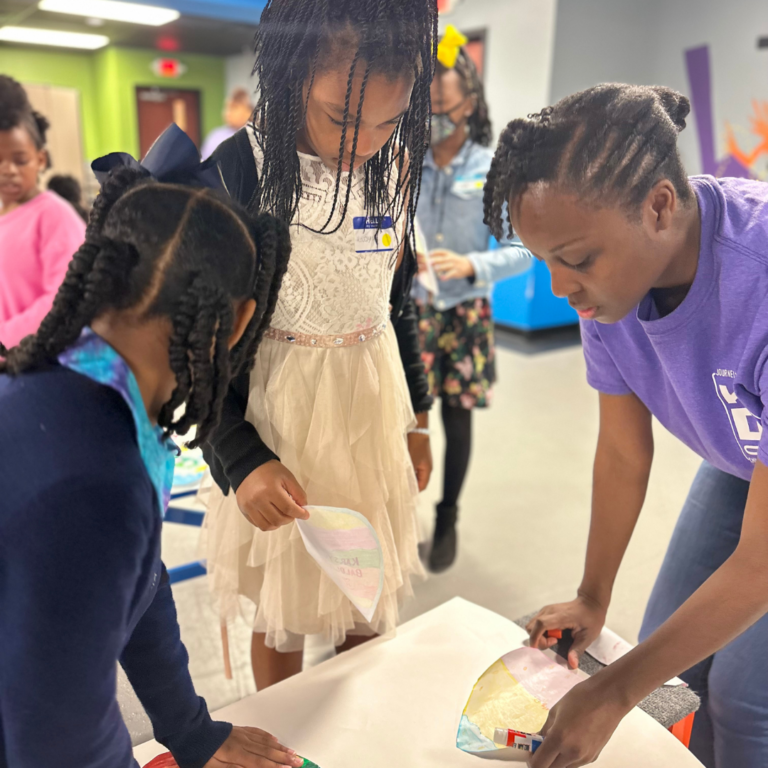 A woman in a purple shirt is standing next to a girl in a white dress