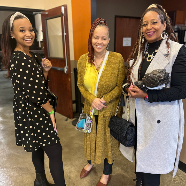 Three women are standing next to each other and smiling