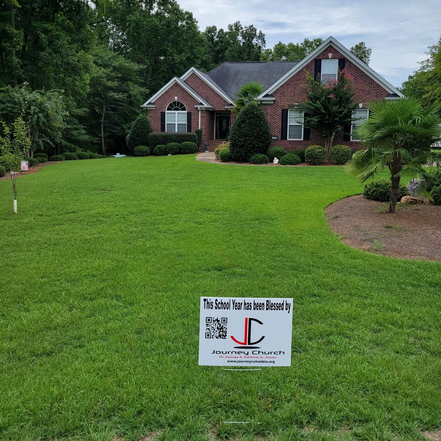 A brick house with a sign in front of it that says jc