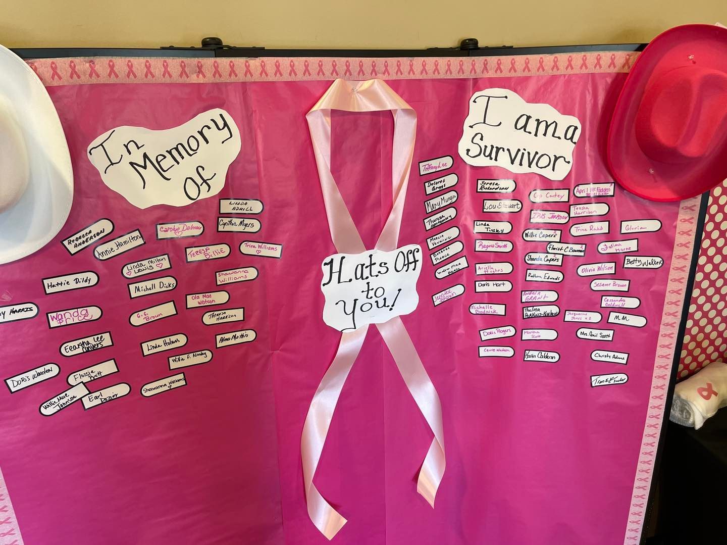 A bulletin board with a pink ribbon and a sign that says i am a survivor