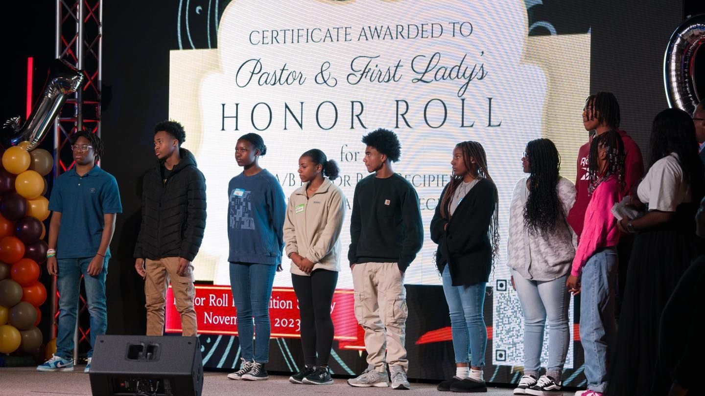 A group of people standing in front of a sign that says honor roll.