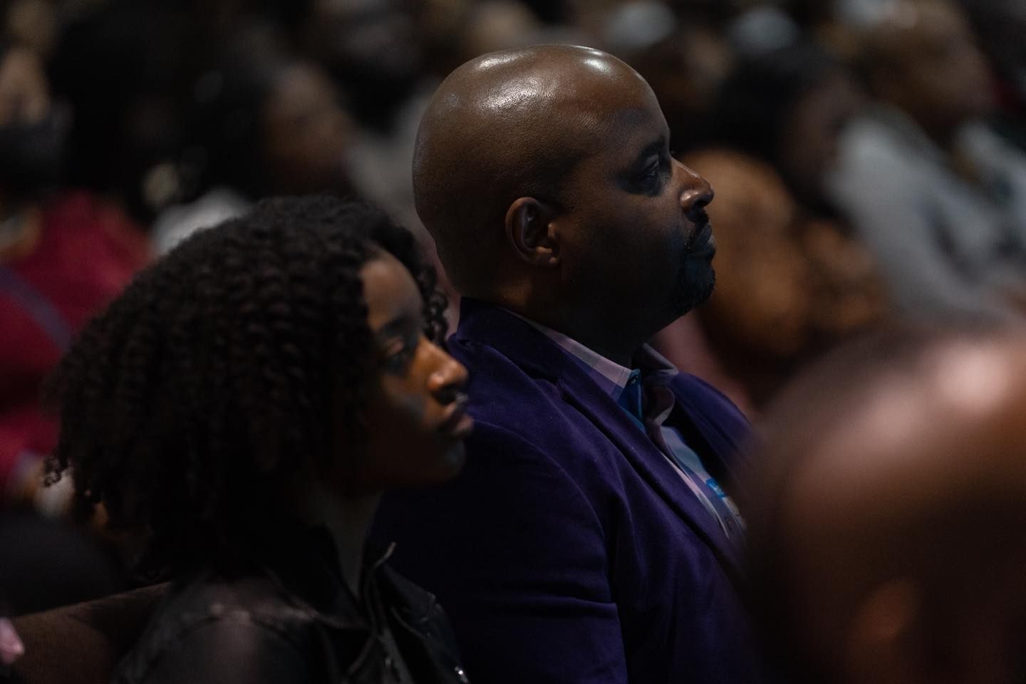 A man and a woman are sitting in a crowd of people.