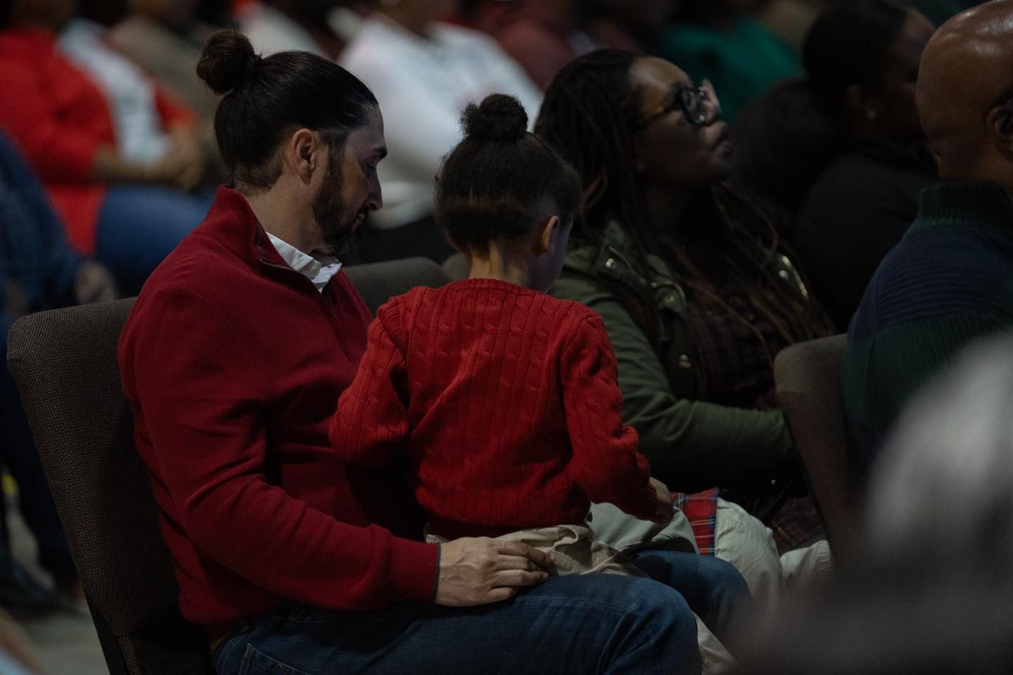 A man and a little girl are sitting in a chair holding hands.