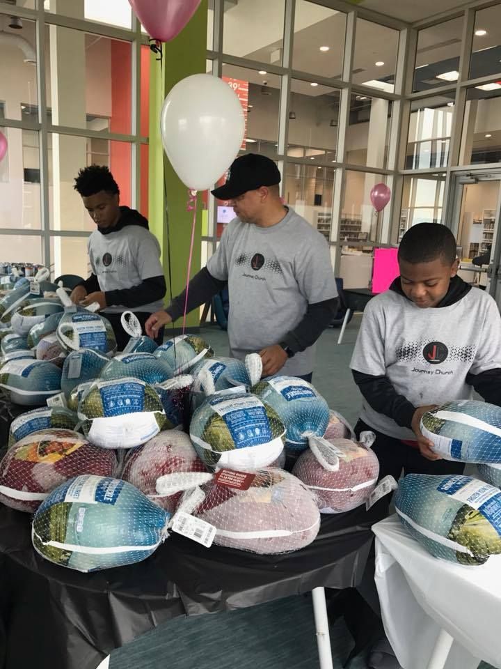 A group of people are standing around a table filled with turkeys.
