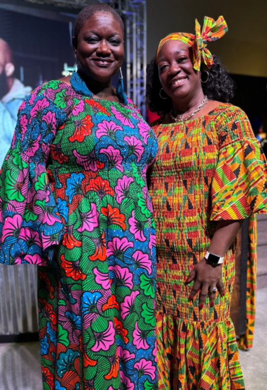 Two women in colorful dresses are posing for a picture.