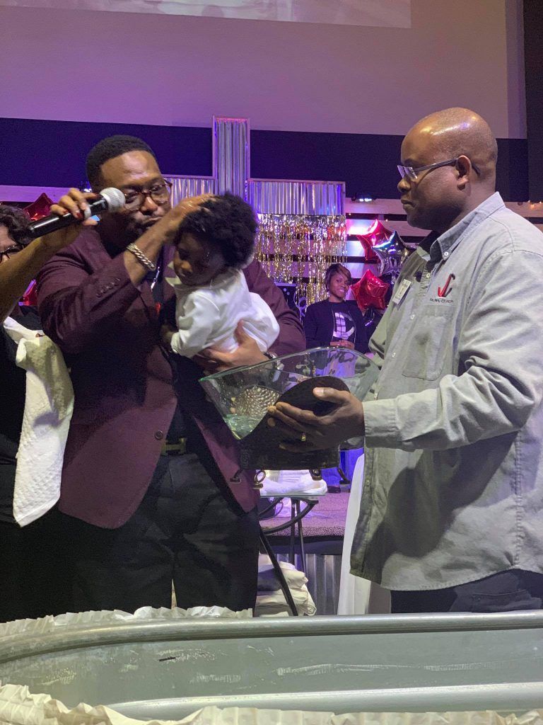 A man is singing into a microphone while holding a baby.