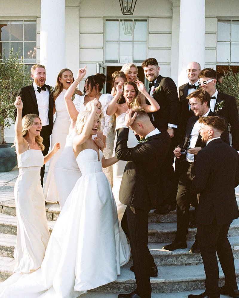 The bride and groom are posing for a picture with their wedding party