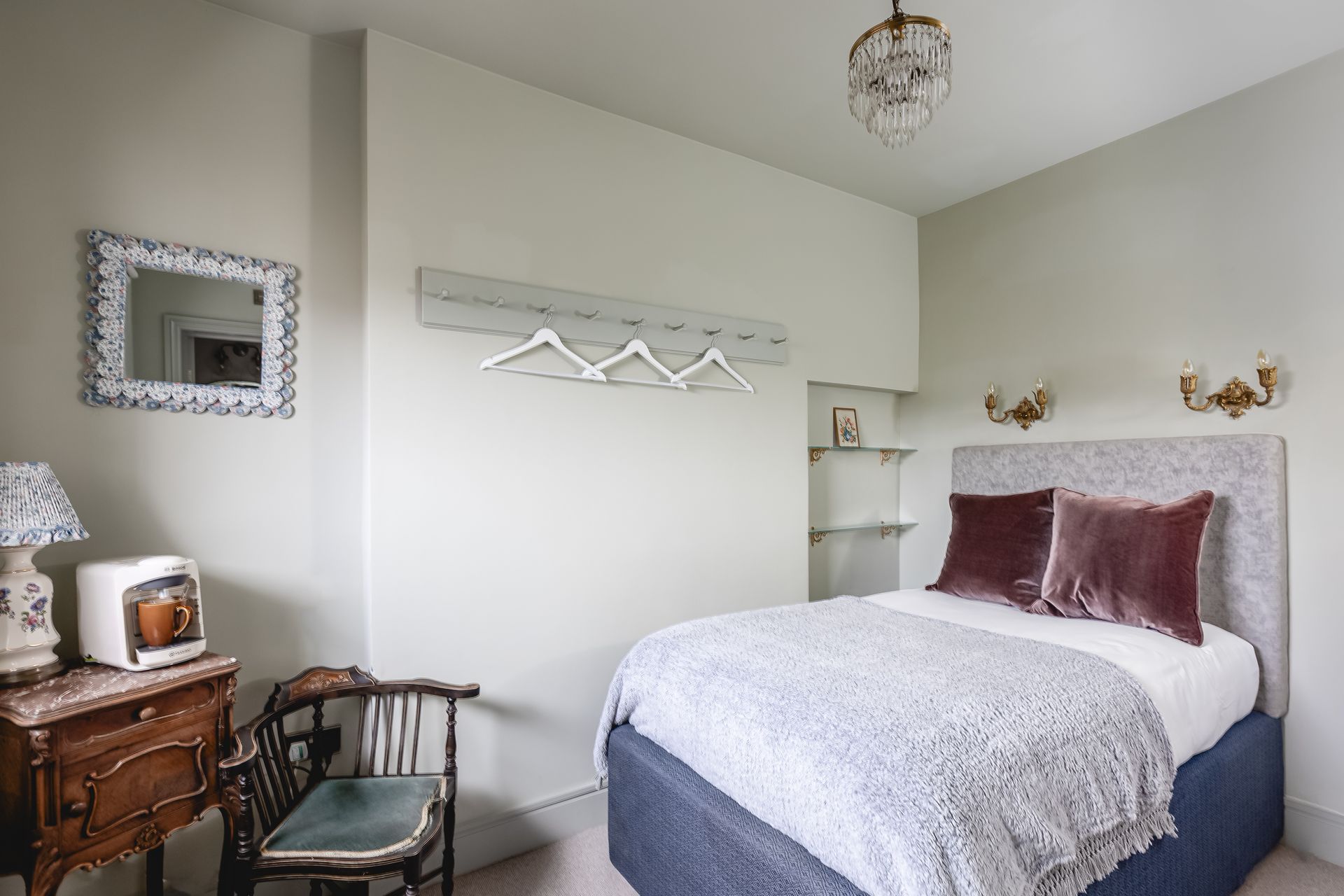 A bedroom with a bed , dresser , chair and mirror.