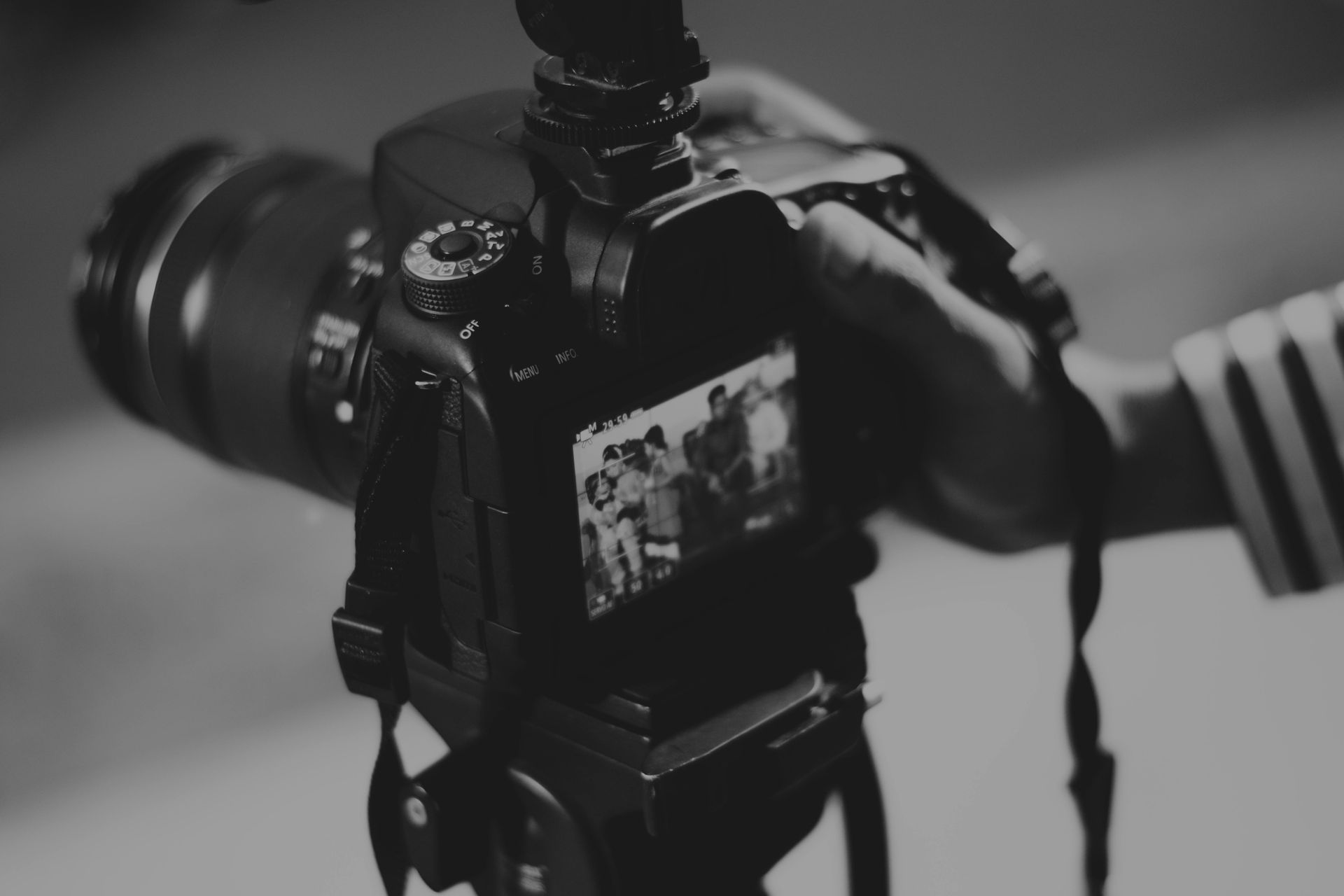 A person is holding a camera in their hand in a black and white photo.