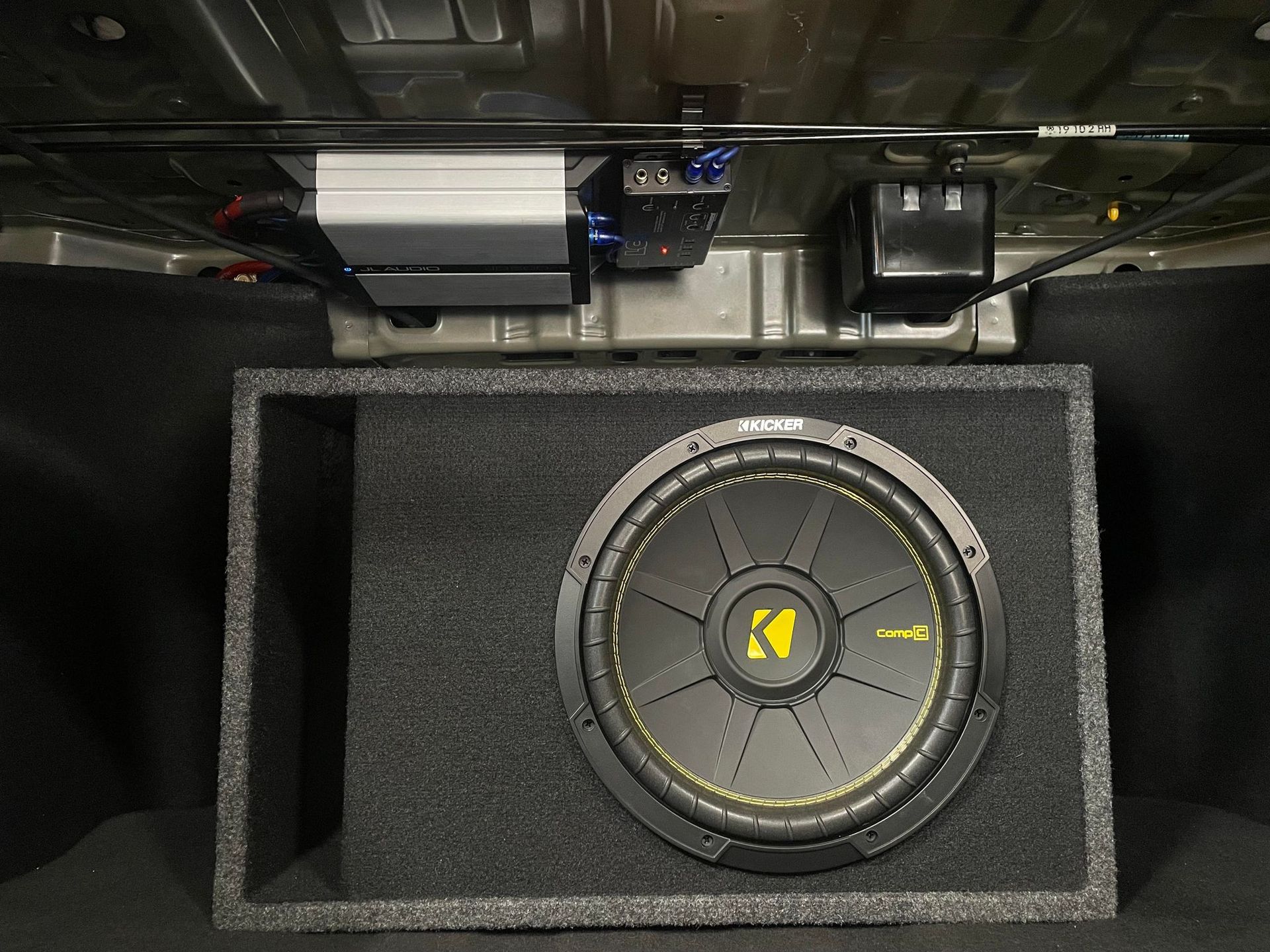 A kicker subwoofer is sitting in the trunk of a car