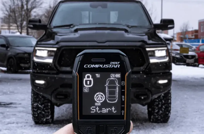 A person is holding a remote control in front of a black truck.