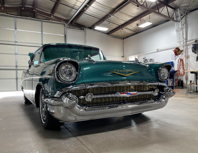 A green classic car is parked in a garage.