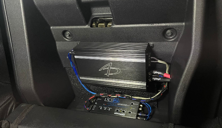 An amplifier is sitting under the dashboard of a car.