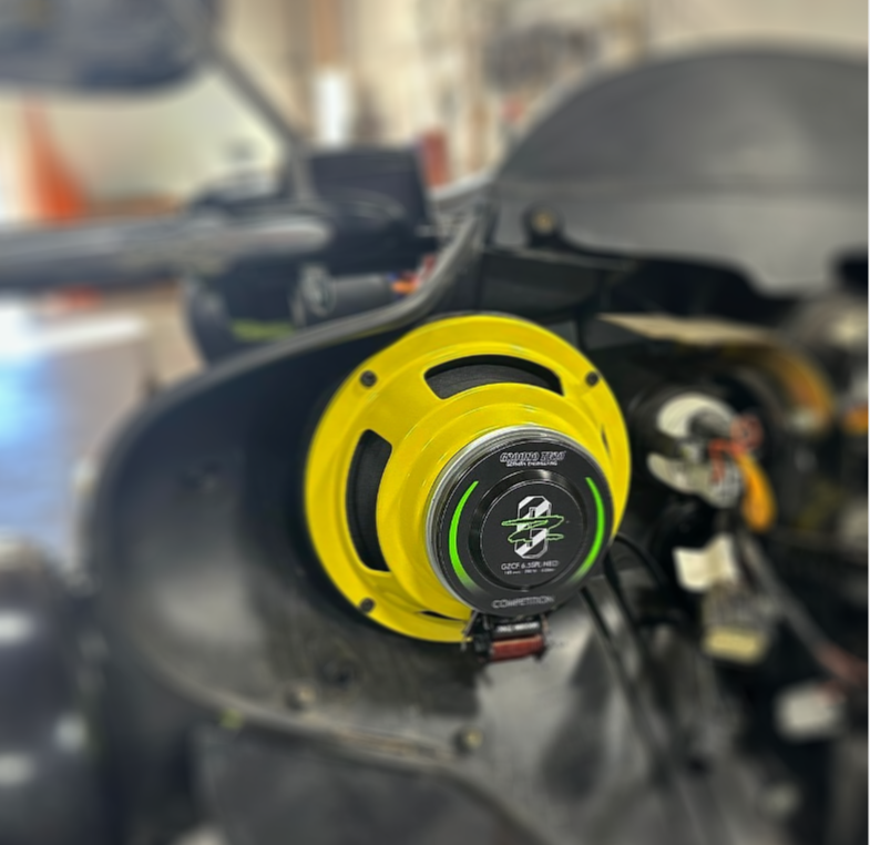 A yellow speaker is attached to the handlebars of a motorcycle