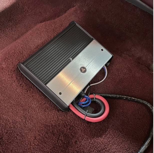 A jl audio amplifier is sitting on a brown carpet