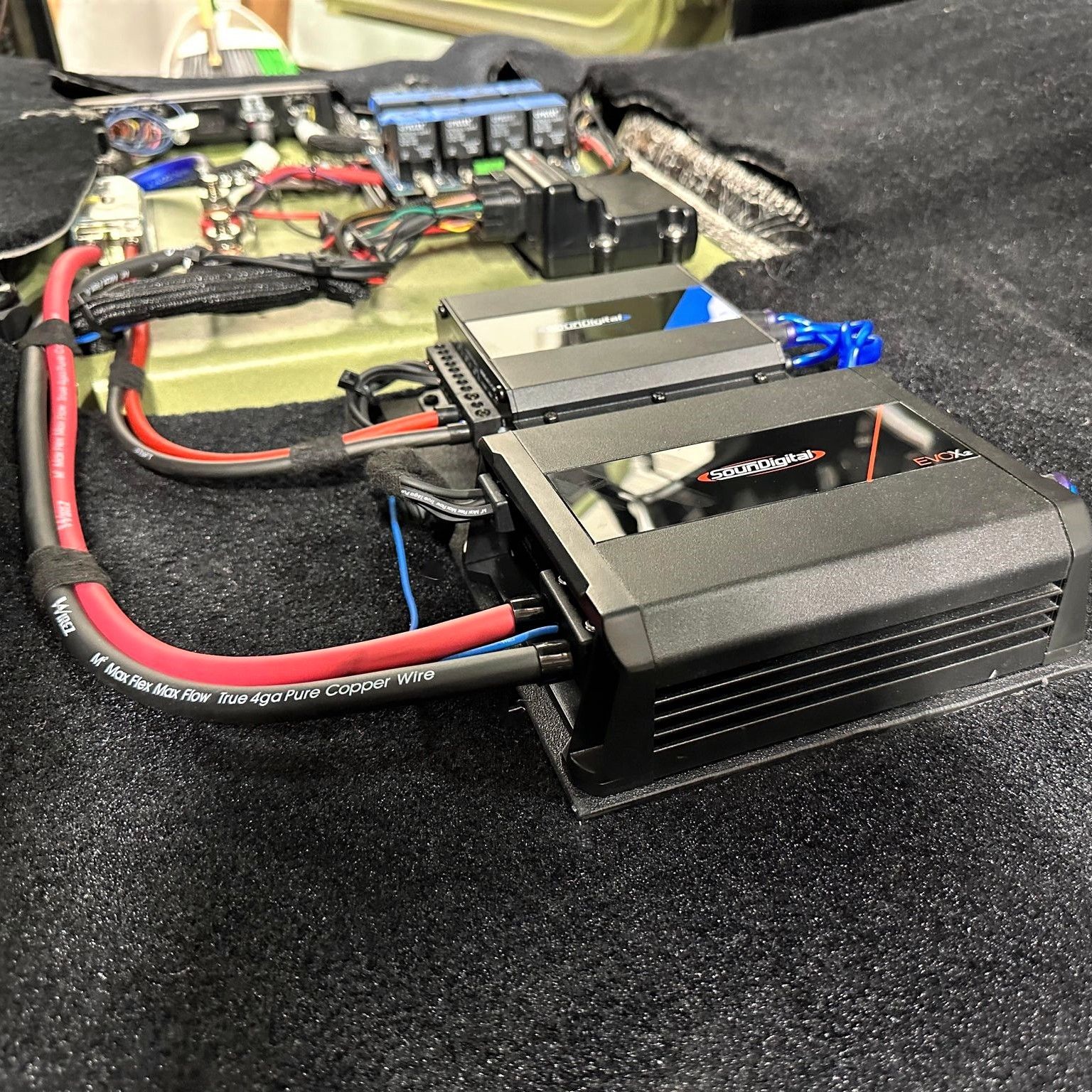 A bunch of wires are connected to a device on the floor of a car.