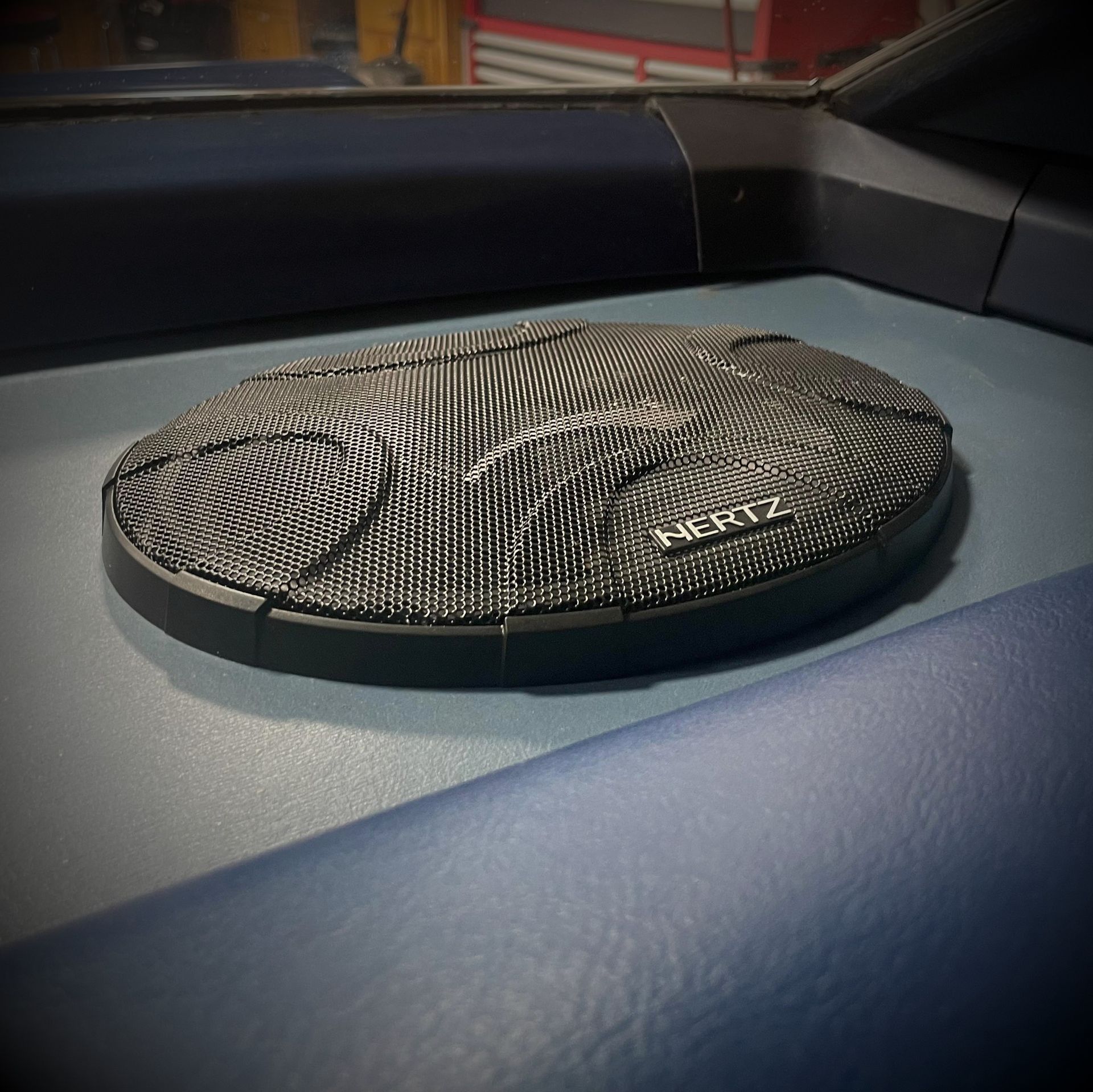 A hertz speaker sits on the dashboard of a car