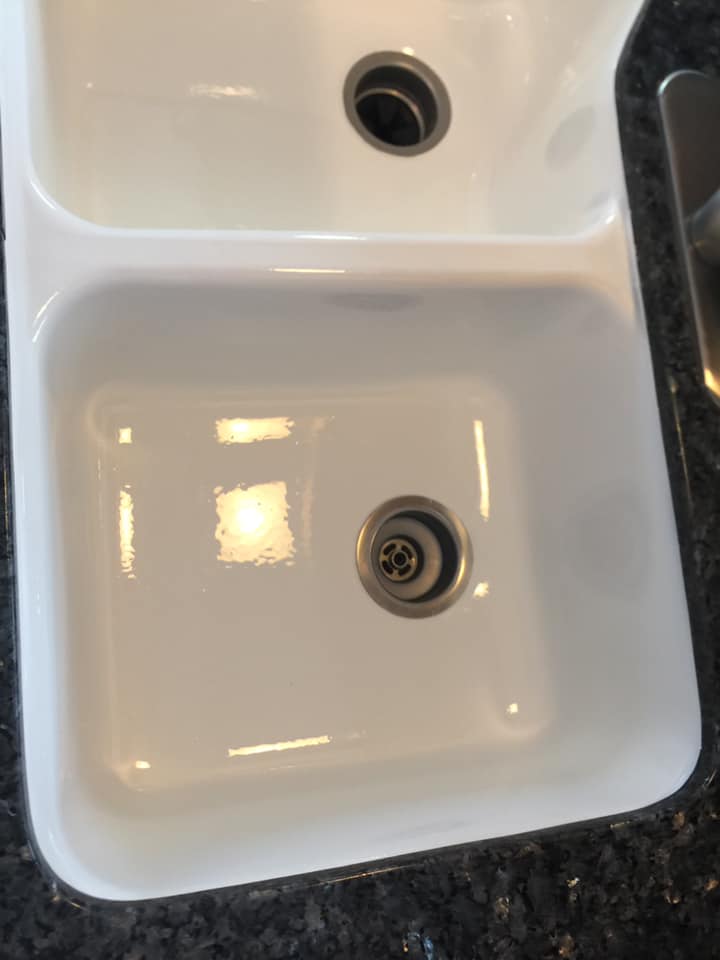 A white kitchen sink is sitting on top of a granite counter.