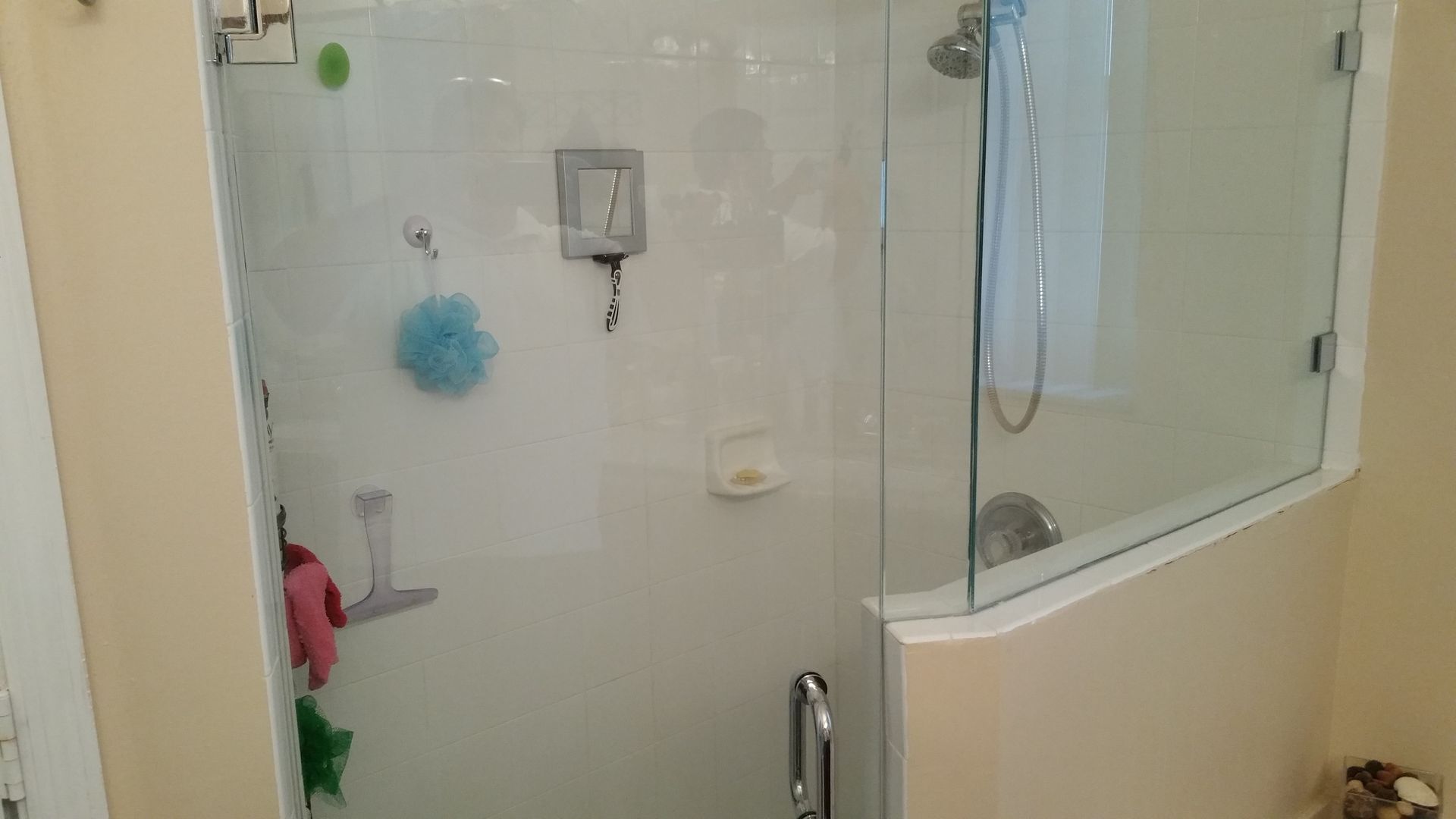 A bathroom with a walk in shower with a glass door.