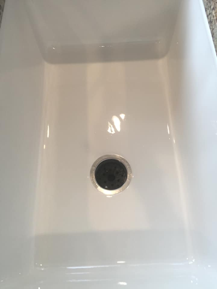 A white sink with a black drain hole in it.