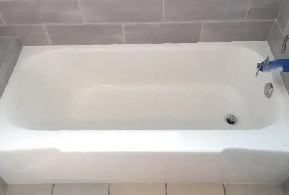 A white bathtub is sitting in a bathroom next to a tiled wall.