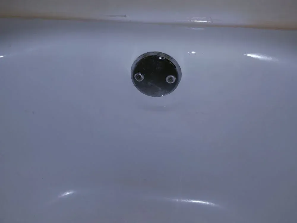 A close up of a bathtub with a drain in it.