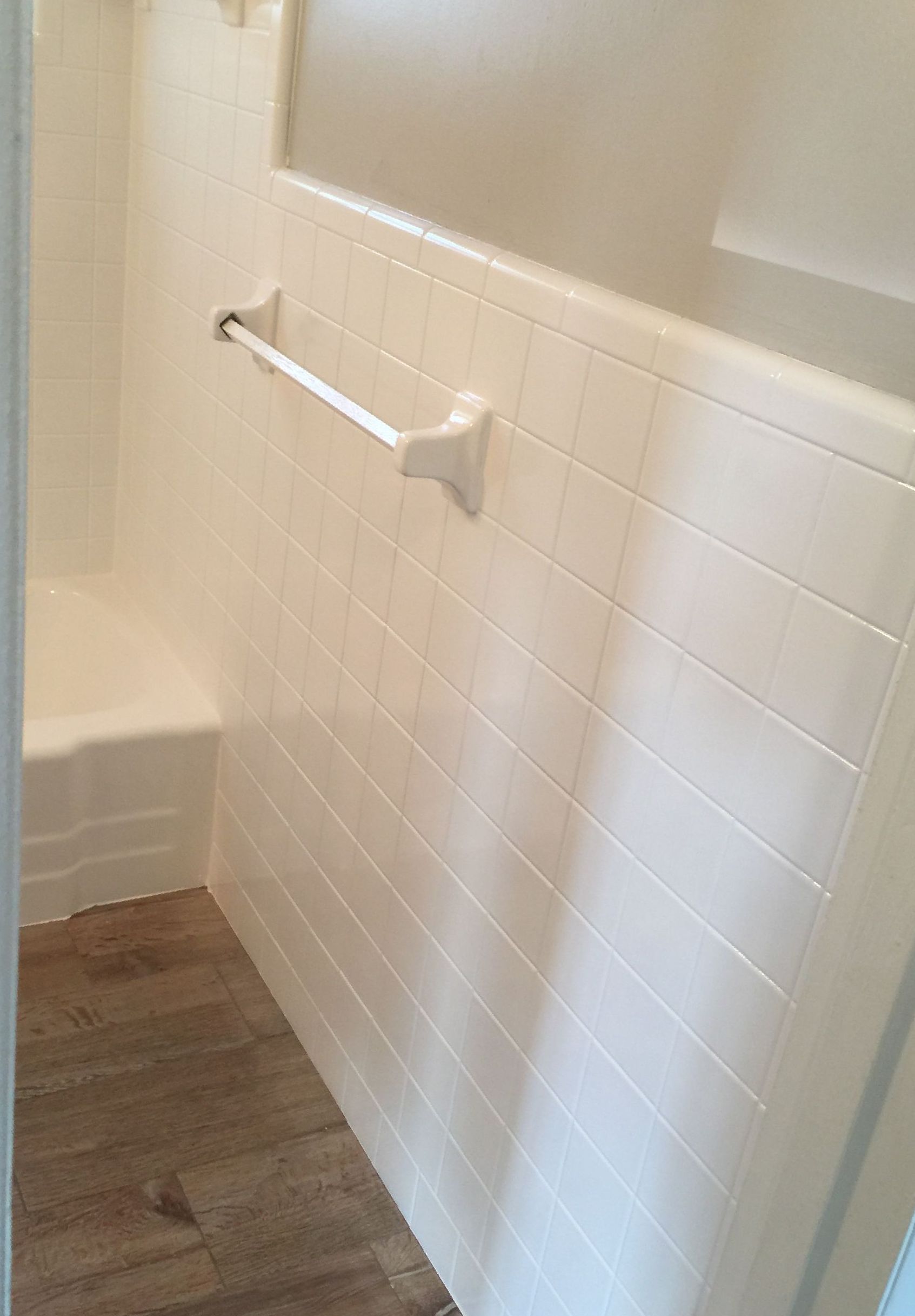 A bathroom with white tile walls and a towel bar.
