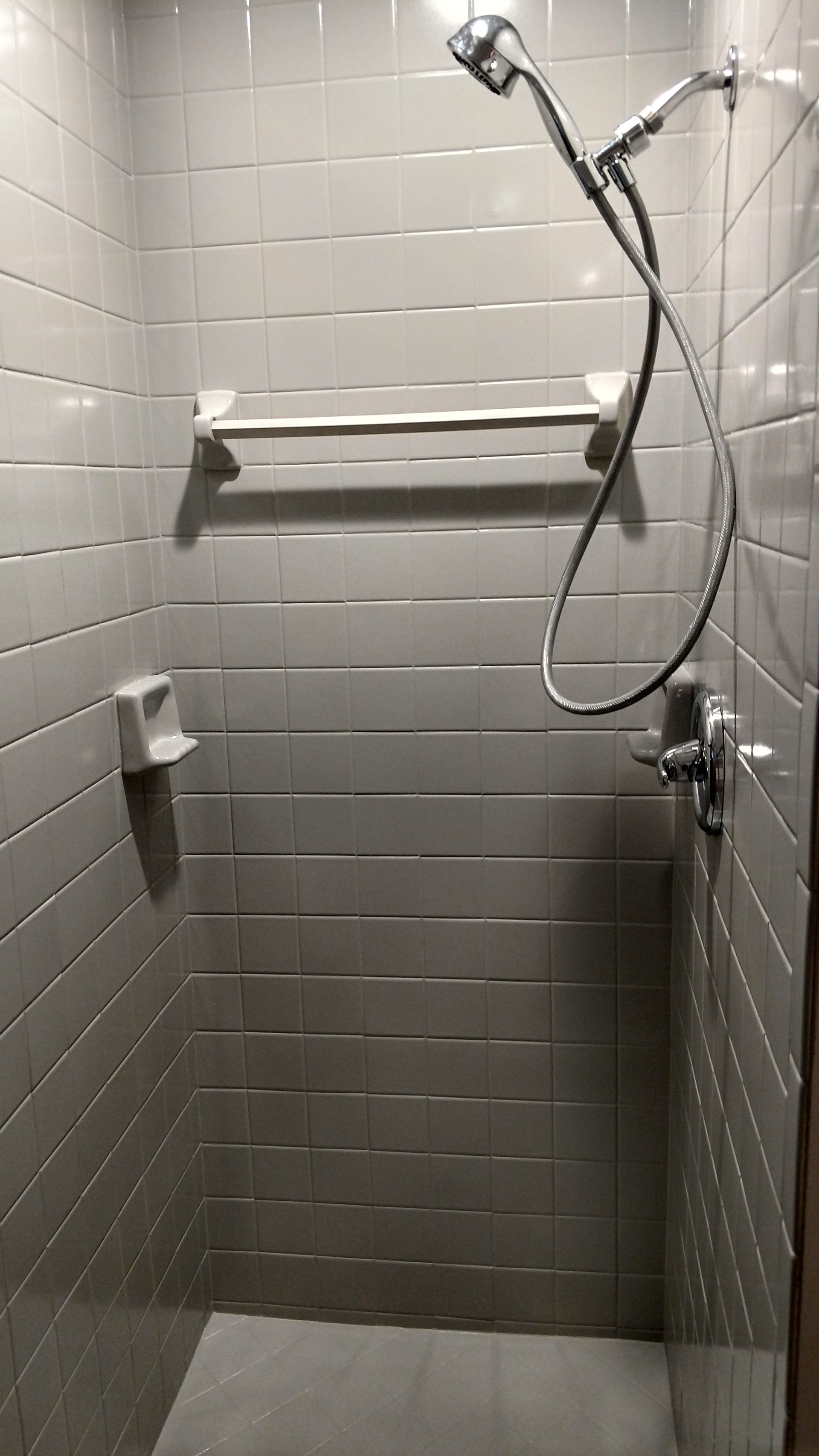 A shower with a shower head and towel racks on the wall.